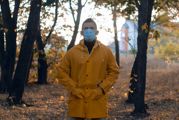 a man in a medical mask in an autumn Park,