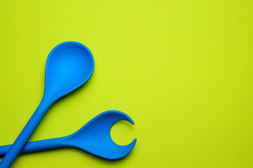 Blue bamboo spoon for salad on a bright yellow background.