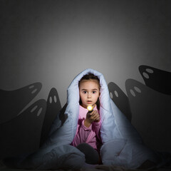 girl under the covers with a flashlight