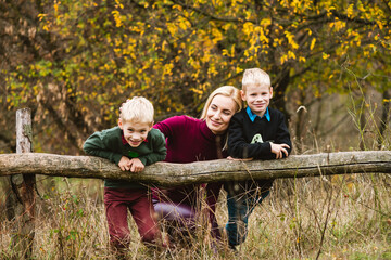 Boys hang on wooden log with mother