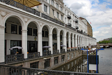 Fototapeta na wymiar The white arches of the Alsterarkaden buildings alongside the Alster river in downtown Hamburg