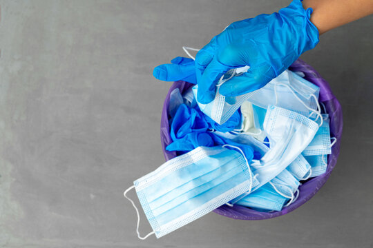 Hand Putting Used Dirty Surgical Mask To A Garbage Bin.