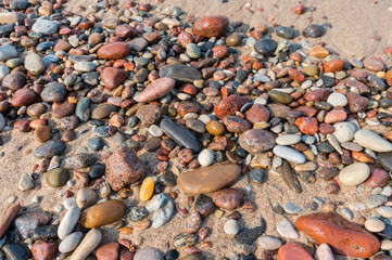 Sea pebbles on the sand. Small smooth stones. Stony seashore.
