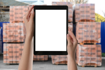 Wholesale trading. Woman using WMS app on tablet at warehouse, closeup