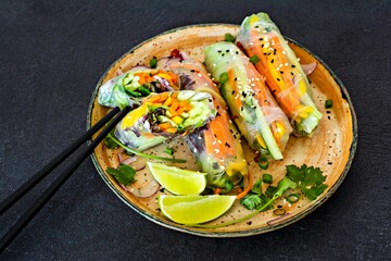 Fresh Asian appetizer Spring rolls (Nem) made from rice paper and raw vegetables and herbs with hot sauce on a dark background. Vietnamese Food