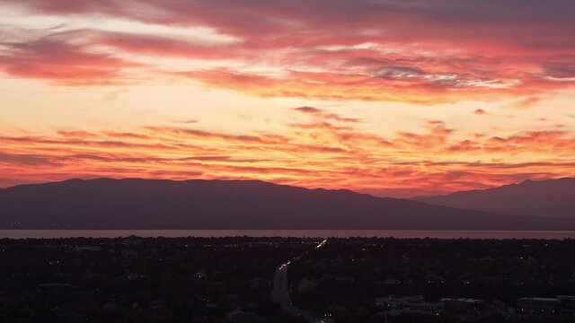 Time lapse of colorful sunset with traffic driving on road through the city of Orem in Utah.