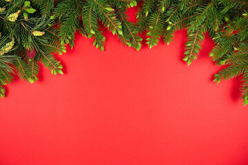 Fototapeta na wymiar Christmas holiday red background, green fir tree branches. New Year flat lay, top view