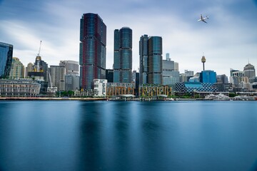 Naklejka premium Passenger aeroplane flying over Sydney City CBD Buildings NSW Australia