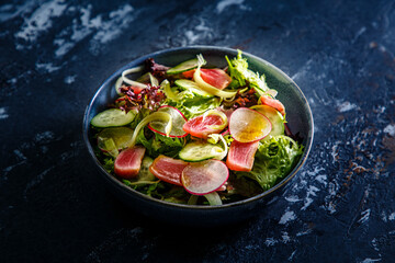 Salad of lettuce, tuna, cucumbers and radishes is on the plate
