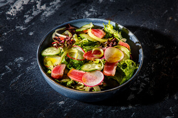 Salad of lettuce, tuna, cucumbers and radishes is on the plate