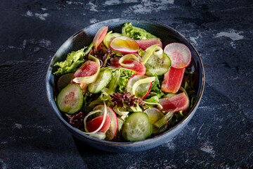 Salad of lettuce, tuna, cucumbers and radishes is on the plate