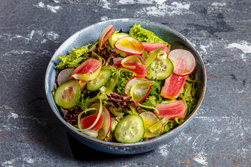 Salad of lettuce, tuna, cucumbers and radishes is on the plate