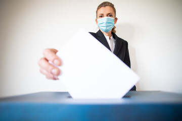 woman wearing mask putting vote in ballot