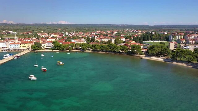 Flyby the shore of the historic town Fazana with harbor and beach in Croatia during daytime in summer