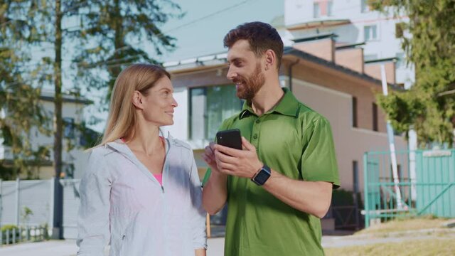 Funny millennial best friends male and female checking smartphone internet application social media connecting and communicating wearing active sportswear working out concept.