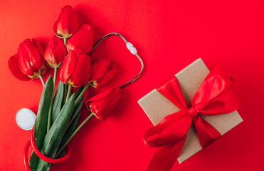 Red tulips and stethoscope on red background. Top view with copy space. Happy Nurse Day.