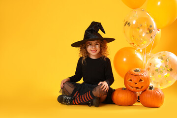Cute little girl with pumpkins and balloons wearing Halloween costume on yellow background