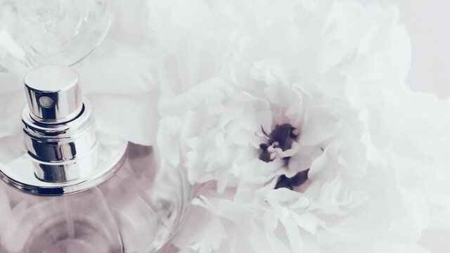 White perfume bottle with peony flowers, chic fragrance scent as luxury cosmetic, fashion and beauty product background, stock footage