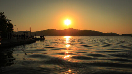 Watching the setting sun behind the mountains from the beach by the sea. Sunset over the sea