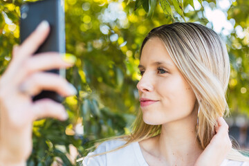 Blond woman takes a selfie outdoors.  Wellness, nature and outdoor concept.
