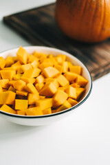 Close up view of fresh, vivid orange pumpkin pieces in a white plate. Healthy and nutritious food.