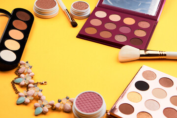 Professional eyeshadows and makeup brushes on a yellow background make-up decoration