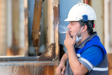 The worker is smoking in the factory.