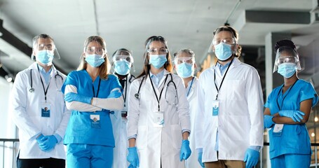Portrait of group of mixed-races professionals males and females doctors in hospital. International group of medics in medical masks. Multi ethnic physicians in pandemic protection in clinic. Covid-19