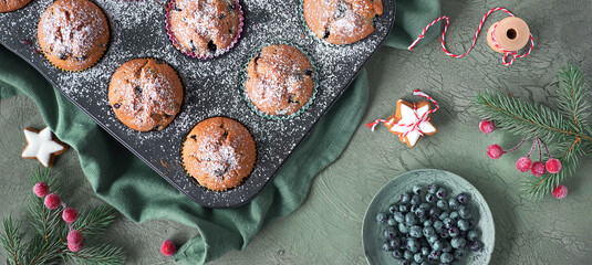 Blueberry muffins with sugar icing in a baking tray. Panoramic top view image with Xmas decor