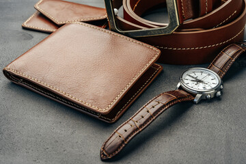 Male watch and leather wallet on dark grey surface