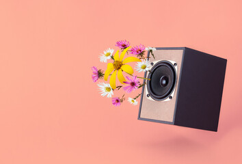 Audio speaker with spring flowers on coral background. Minimal spring vibe concept.