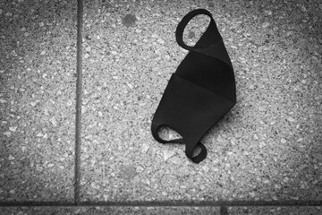 A black mask discarded on the pavement