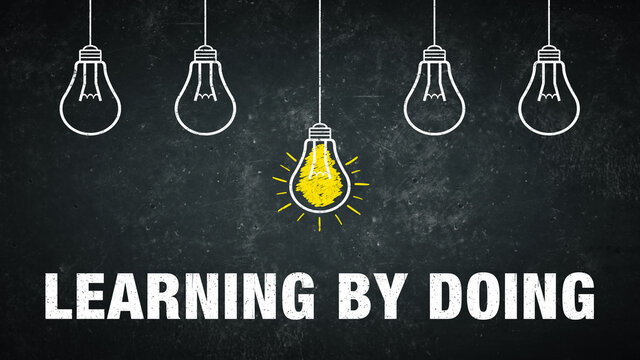 Phrase „learning by doing“ on a rustic background with 5 light bulbs.