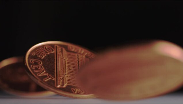 Super slow motion shot of pennies spinning around against a dark background