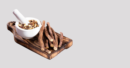 Licorice herb root used in chinese herbal medicine in a mortar with pestle and spoon. Glycyrrhiza glabra.