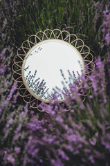 round mirror lies in lavender flowers top view background
