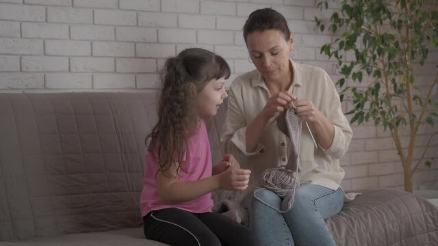 Mother knit with child. A mother knit and show the handmade socks to her child.