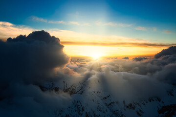 Beautiful and striking aerial view of the puffy clouds over the mountains during a colorful sunset. Taken near Vancouver, British Columbia, Canada. Magical Nature Background