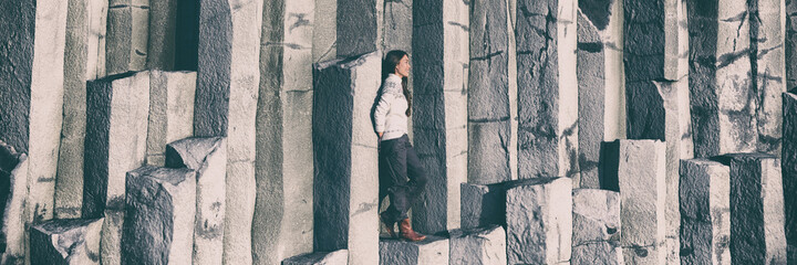 Iceland tourist at beach climbing on basalt columns on Reynisfjara beach, the black sand beach of...