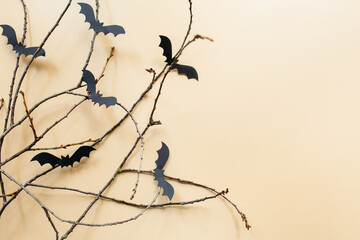 Halloween decorations with bats and branches on pastel beige background. Halloween concept. Flat lay, top view, copy space