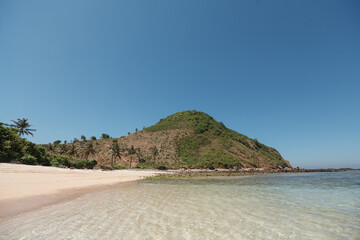 Tropical seasape. View on empty white sand beach with rocks and palm trees on Lombok island. Travel Indonesia