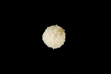 Popular coconut sweets, round white candies in coconut flakes, isolated on a black background