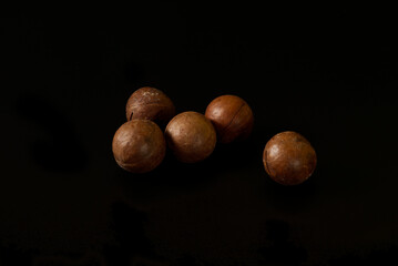 five macadamia nuts isolated on black background