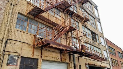 Tan building back with patinaed fire escapes and windows. (Landscape Orientation)