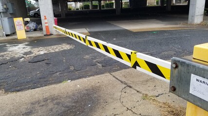 Yellow and black security arm at parking lot entrance.