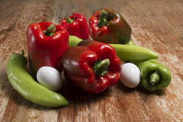 red bell pepper (capsicum annuum) and green pepper on an aluminum plate or dish on a black background