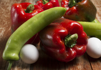 red bell pepper (capsicum annuum) and green pepper on an aluminum plate or dish on a black background
