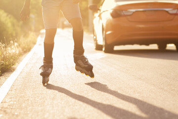 one unrecognizable person skating with rolling skates on a rural paved street ,lower body and back...