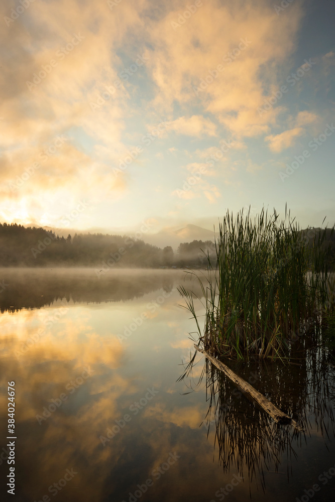 Wall mural beautiful sunrise over mineral lake in washington state. calm morning with clouds and reflections