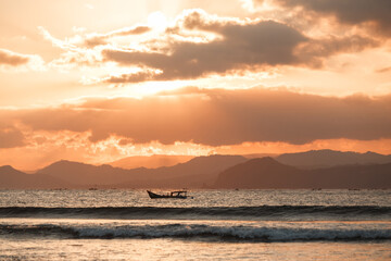 Fototapeta na wymiar Lonely boat in the ocean by unset with mountains in the horizon. Sunset Over Lombok Island, Indonesia
